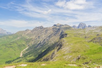 Extensive mountain landscape with green hills and blue sky in the background, Schlehrn hike, Alpe