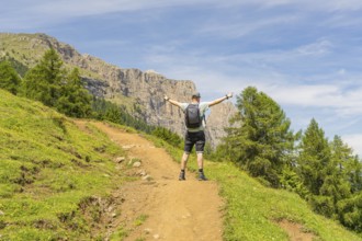 A hiker with outstretched arms on a mountain path, surrounded by green nature, Schlehrn hike, Alpe