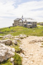 Rustic mountain hut at the end of a hiking trail, surrounded by green meadows, hike to the
