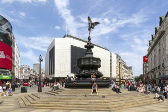 People sitting around Eros statue, Piccadilly Circus, central London, England, UK - Shaftesbury
