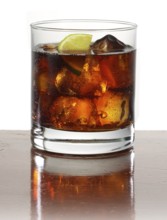 Cocktail in a tumbler on ice with half a slice of lime as garnish against a white background,