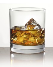 Whisky on ice in a tumbler in front of a white background