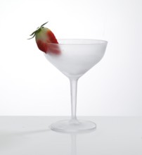 Empty, frosted cocktail glass with strawberry garnish against a white background, studio shot