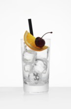 Betautes long drink glass, filled with ice cube cubes, half orange slice and cherry as garnish, in