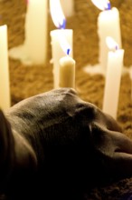 Hand placing a candle as an offering during prayers at a religious festival