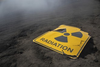 Damaged radiation warning sign in scorched earth. Symbol of catastrophe and nuclear ruin.