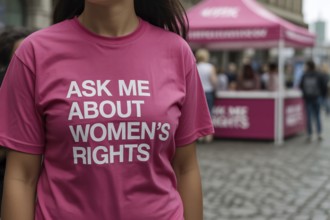Woman in pink shirt with feminist message As me about women's rights at street info booth.