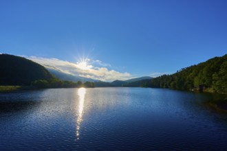 Lake in the morning light with sun, blue sky and surrounding mountains, summer, Rursee, Obersee,
