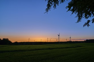 Silhouettes of wind turbines rise into the colourful morning sky as the sun rises behind the