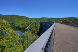 Long, curvy bridge with dam and surrounding forest under a clear sky, summer, Urft dam wall,