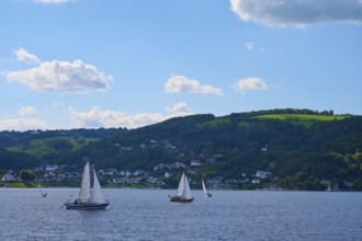 Sailing boats on a calm lake, surrounded by green hills and white cloudy sky, summer, Rursee,