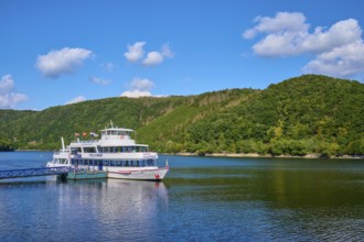Passenger ship anchored at the jetty, in front of green hills under a blue sky, summer, Rursee,