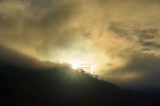 Sunrise breaks through fog over a mountain, dramatic play of light, summer, Rursee, Obersee,