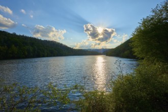 Sunset over a lake with wooded hills, clear reflection on the water surface, summer, Rursee,