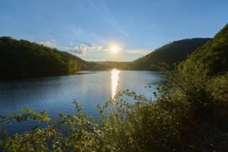 Sunset over a calm lake with green hills in the background, summer, Rursee, Obersee, Simmerath,