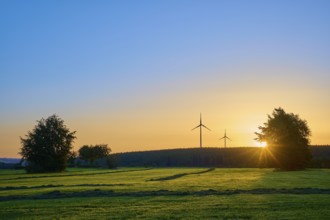 Wind turbines in a natural landscape at sunrise, with warm incidence of light, summer, Rohren,