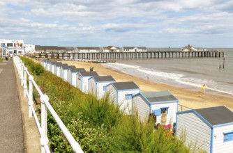 View over beach huts to sandy beach and pier, Southwold, Suffolk, England, UK