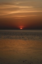 Atmospheric sunset... Cuxhaven, North Sea, in calm weather, glowing red sun sinking into the sea,