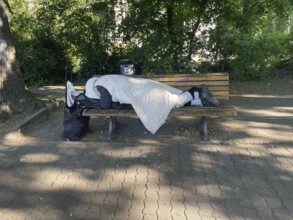 Homeless man sleeping on a park bench in Viktoriapark, District Friedrichshain-Kreuzberg, Social