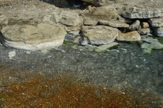 Rocky shore with clear and gently foaming waves, natural textures, Embros Thermal Baths, Kos,