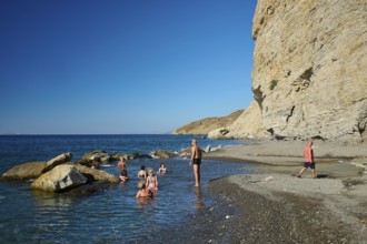 People enjoying the sea on a rocky beach under a clear blue sky, Embros Thermae, Kos, Dodecanese,