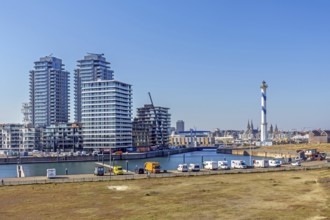 Motorhomes parked in front of lighthouse Lange Nelle and skyline of the Oosteroever quarter in