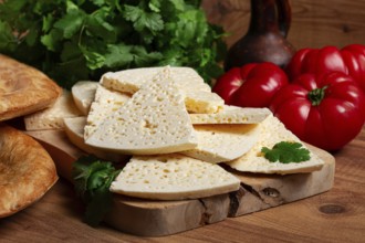 Georgian sliced cheese, on a wooden chopping board, with tomatoes with herbs and lavash, rustic