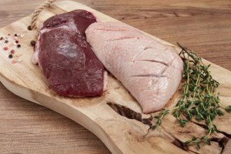 Fresh raw duck breasts, on a wooden chopping board, with herbs and spices, no people