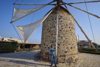 Stone mill with sails, a man pulling a rope under a blue sky, windmill, Antimacheia, Kos,