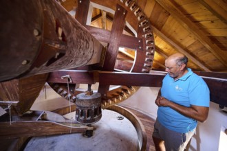 Man looking at the wooden gears of a windmill, Windmill, Antimacheia, Kos, Dodecanese, Greek