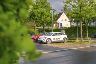 An electric car parked in the sunset on a quiet street surrounded by trees, Deer E, car sharing,