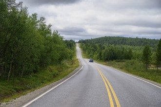 A lonely road leading through a green, wooded hilly landscape of Finland's countryside, Karelia,
