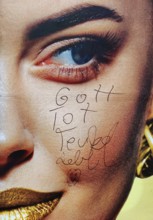 Large-scale advertising poster depicting a woman's face and the inscription Gott tot, Teufel lebt,