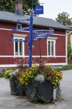Street scene in the old town of Naantali, colorful signposts and flowers in front of a red wooden