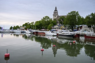 Marina Port of Naanatali with boats and a church surrounded by trees, a peaceful maritime scene,