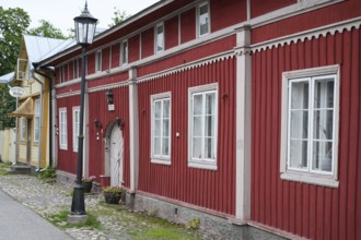 Street scene in the old town of Naantali, red historic wooden building with decorative windows on a