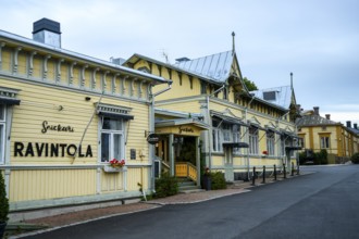 Yellow restaurant building with decorative wooden design, located on a quiet street, conveys