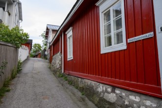 Street scene in the old town of Naantali, alley with red wooden buildings and white windows. A