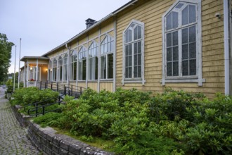 Street scene in the old town of Naantali, yellow building with tall, narrow windows and shrubs