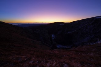 Sunrise over dark mountains with purple sky at dusk, looking towards the Rhine Valley, Martinswand,