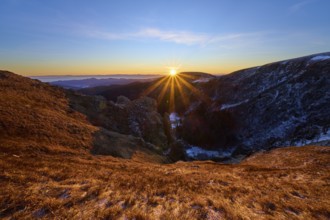 Golden sunbeams over mountain landscape under clear blue sky, looking towards the Rhine Valley,