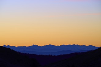 Mountains in silhouette at sunrise, sky in blue and orange, looking towards Alps, Hohneck, La