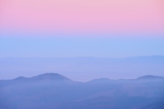 Pale hills in evening fog under a pink sky, looking towards the Rhine Valley, Hohneck, La Bresse,