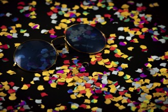 Sunglasses on colorful confetti against black background, Mardi Gras
