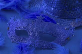 Blue mask with matching feathers and hat on blue background, carnival