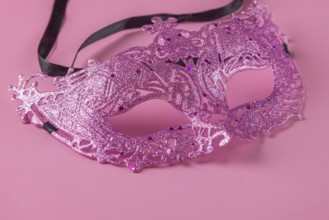 Glittering pink mask lying on a pink background