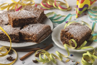 Spice cake with powdered sugar surrounded by colorful streamers and confetti