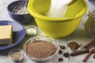 Sugar is emptied into dough bowl surrounded by baking ingredients