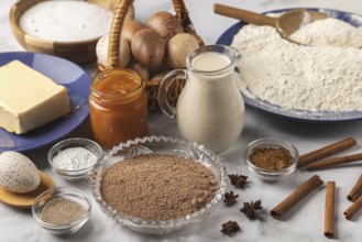 Baking ingredients, flour, sugar, cinnamon, milk, butter, cocoa, jam and eggs on a table