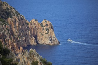 Visitors on an excursion boat look at bizarre rock formations at Capo Rosso, Piana, Corse-du-Sud